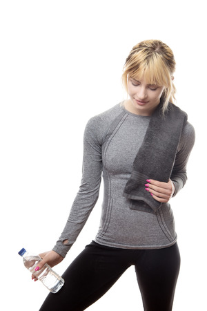 blonde hair woman wearing a grey sports top holding a water bottle and a towel around her neckの写真素材