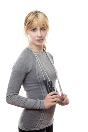 standing fitness woman in a grey top with a skipping rope around her neckの写真素材