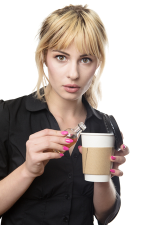 blonde haired business woman putting alcohol into her take away cupの写真素材