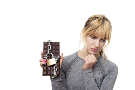 fitness woman holding a chocolate bar locked up in chainsの写真素材