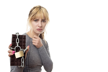 fitness woman holding a chocolate bar locked up in chainsの写真素材