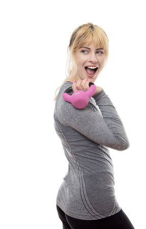 blonde hair woman wearing a grey sports top holding a kettlebellの写真素材