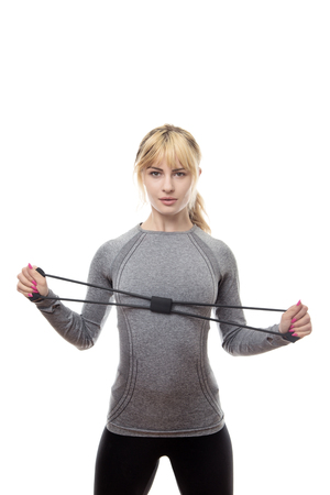 blonde haired woman wear a grey sports top using a rubber band for resistance trainingの写真素材