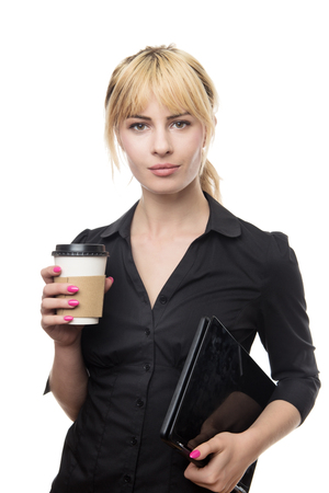 standing blonde haired business woman holding a coffee cup and a computerの写真素材