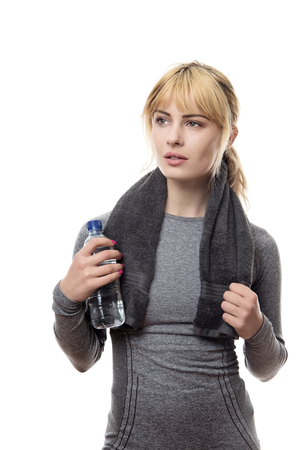 blonde hair woman wearing a grey sports top holding a water bottle and a towel around the neckの写真素材