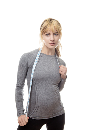 blonde haired fitness woman wearing a grey top with a tape measure around her neckの写真素材
