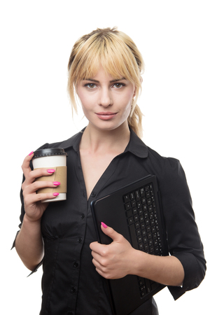 standing blonde haired business woman holding a coffee cup and a computerの写真素材
