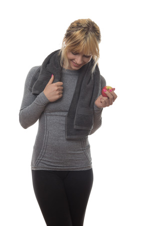 blonde hair woman wearing a grey sports top holding a apple and a towel around her neckの写真素材