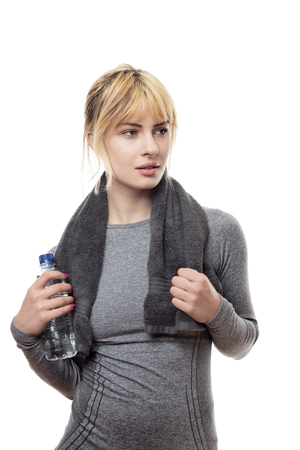 blonde hair woman wearing a grey sports top holding a water bottle and a towel around the neckの写真素材