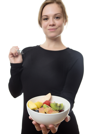 happy fitness woman all in black eatting a fruit saladsの写真素材