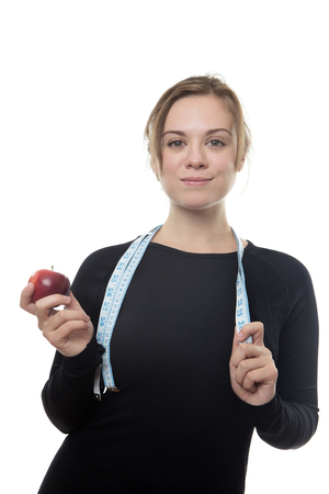 happy fitness woman all in black holding a apple and a tape measure around her neckの写真素材