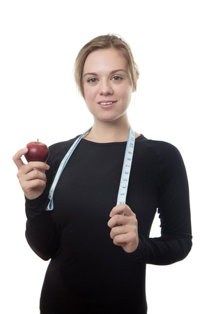 happy fitness woman all in black holding a apple and a tape measure around her neck の写真素材
