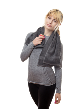 blonde hair woman wearing a grey sports top holding a apple and a towel around her neckの写真素材