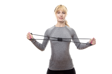 blonde haired woman wear a grey sports top using a rubber band for resistance trainingの写真素材