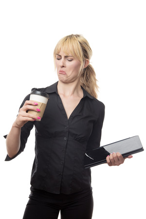 standing blonde haired business woman holding a coffee cup and a computerの写真素材