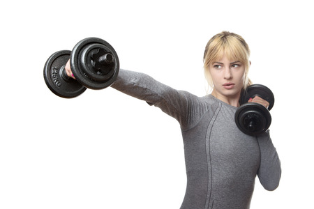 blonde haired woman using dumbbells punching the air in front of herの写真素材
