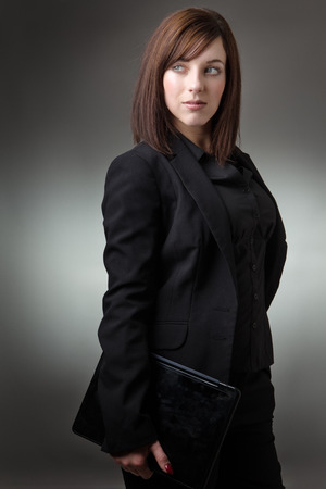 young business woman holding a laptop shot in the studio on gray backgroundの写真素材