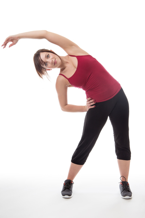 shot in the studio of young fitness woman standing stretching her arms and bodyの写真素材