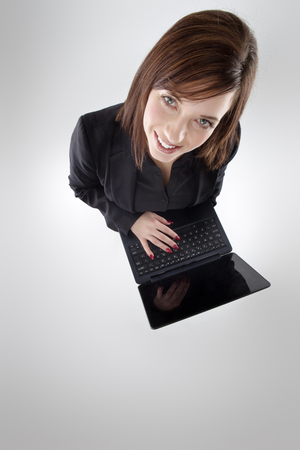 business woman shot from above looking up at camera using a laptopの写真素材