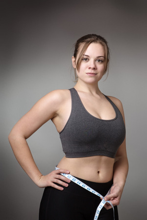 fitness model holding a tape measure around her waistの写真素材