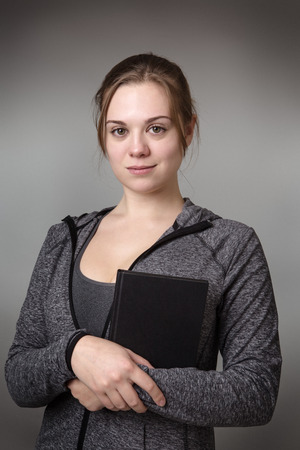 young fitness model holding a hard back bookの写真素材