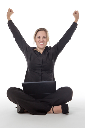 happy business woman sitting on the floor using a laptop computer with her arms in the air for joyの写真素材