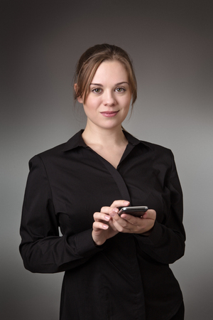young business woman texting on a mobile phone shot in the studio on a grey backgroundの写真素材