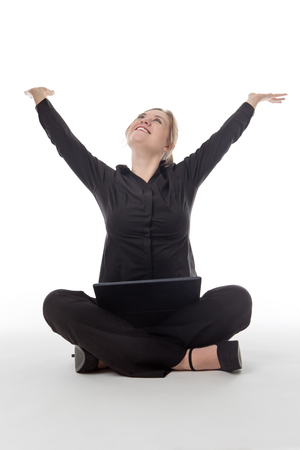 happy business woman sitting on the floor using a laptop computer with her arms in the air for joyの写真素材