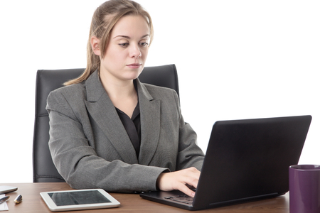 business woman sitting a a desk with a laptop computer in front of her の写真素材