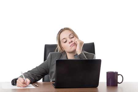business woman sitting a a desk with a laptop computer in front of her の写真素材