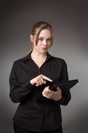 young business woman using a computer shot in the studio on a grey backgroundの写真素材