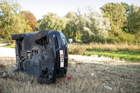 car on its rolled onto its side in a field after going to fast around cornerの写真素材
