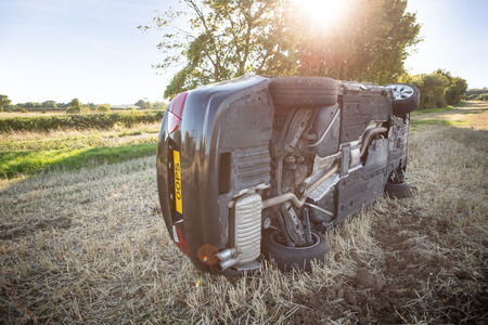 car on its rolled onto its side in a field after going to fast around cornerの写真素材