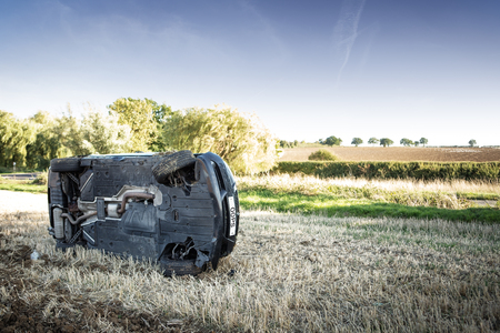 car on its rolled onto its side in a field after going to fast around cornerの写真素材