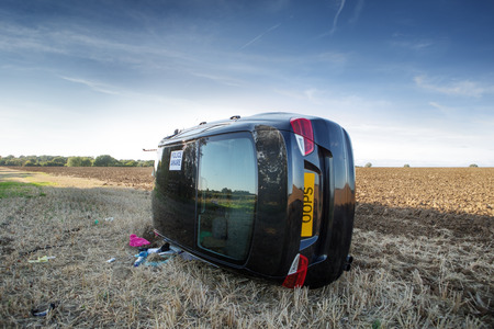 car on its rolled onto its side in a field after going to fast around cornerの写真素材