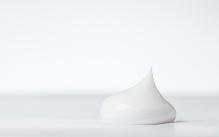 close up detail of single drop of beauty cream on white back groundの写真素材