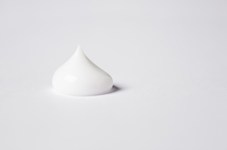 close up detail of single drop of beauty cream on white back groundの写真素材