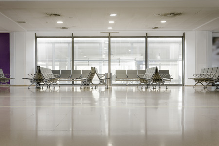 chairs by a window of a airport terminal gate waiting to flightの写真素材
