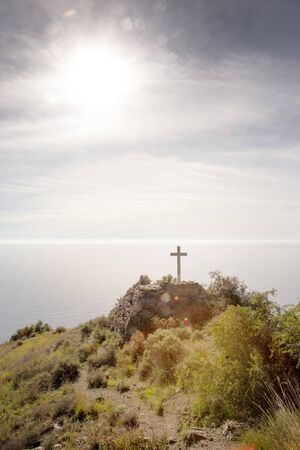 small cross on mountain side looking out to sea