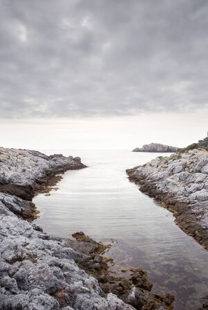rocky beach in spain looking out to sea as the sun is settingの写真素材