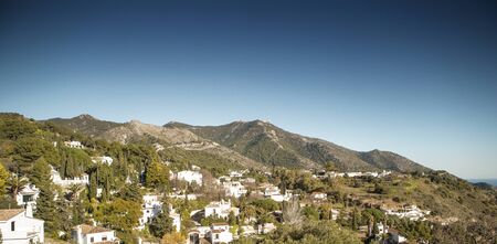 hillside town of mijas with lots of whitewash building and homes build into the hillsideの写真素材