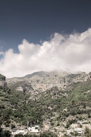 looking up at the mountains with house build into the cliff side in positano in italyの写真素材