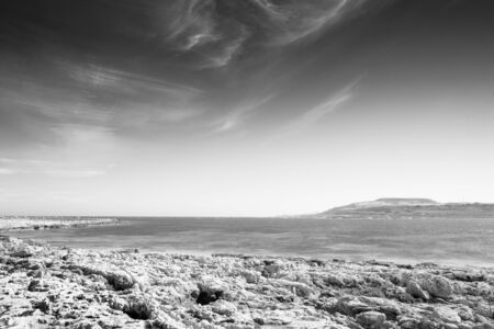 rocky beach in malta looking out to the sea with a cloudy skyの写真素材