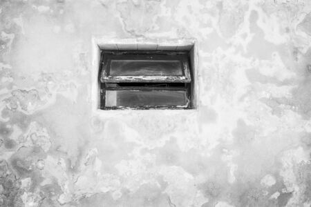 wooden window in an old textured concrete wall on a buildingの写真素材