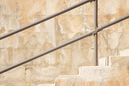 side view of steps and handrail against a concrete wallの写真素材
