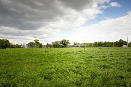 train going past set in a beautiful landscape image of the essex countrysideの写真素材