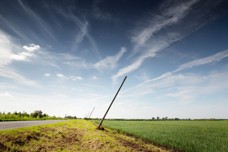 telephone poles leaning over from the wind along a countryside road in englandの写真素材