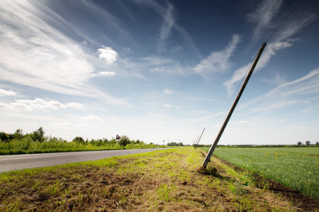 telephone poles leaning over from the wind along a countryside road in englandの写真素材