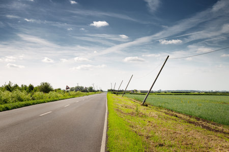 telephone poles leaning over from the wind along a countryside road in englandの写真素材