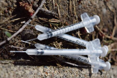 Used insulin needles discarded in a park. Junkie trash. Drug addiction in urban area.の写真素材